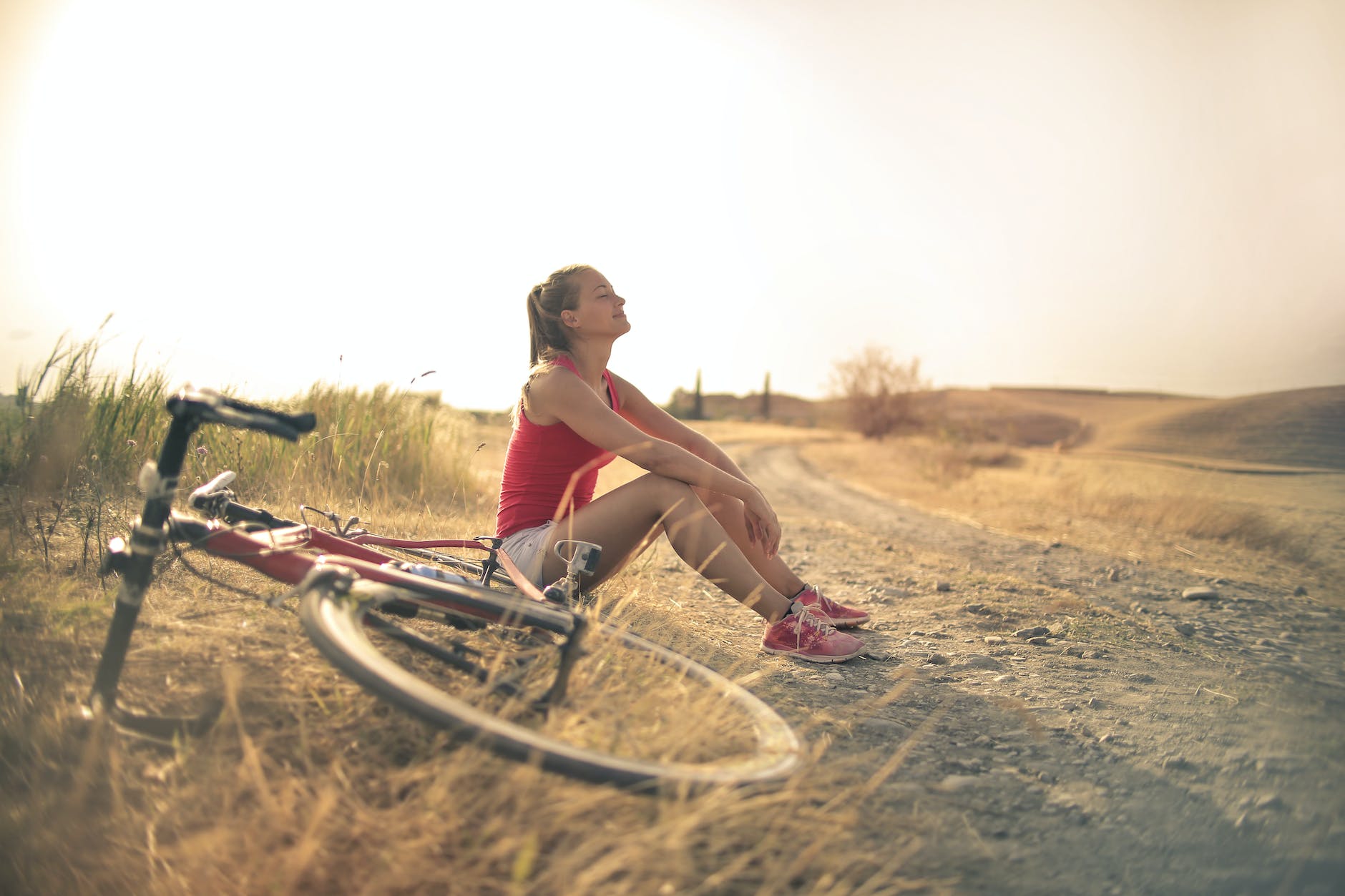 Best Natural Women's Healthcare Services Naturopathic Functional Medicine sportive woman with bicycle resting on countryside road in sunlight